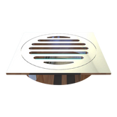 Square stainless steel shower drain grate with circular slotted bars, modern chrome finish on wood floor.