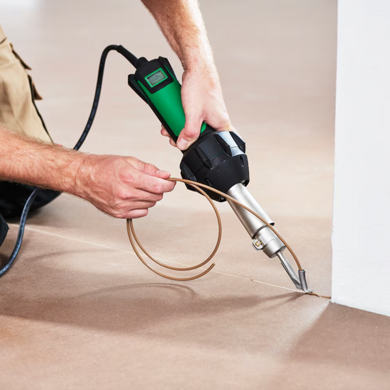 Green corded hot air welding gun with digital display and flexible nozzle, welding vinyl floor seam by wall